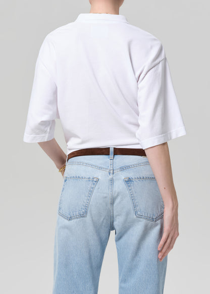 Person wearing a white shirt and light blue jeans on a plain background