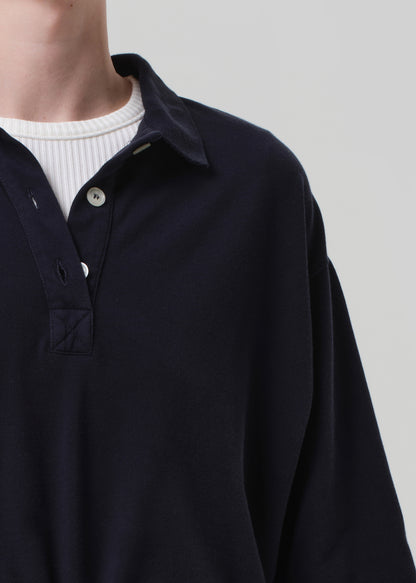 Person wearing a dark blue long-sleeve shirt over a white sweater on a light gray background