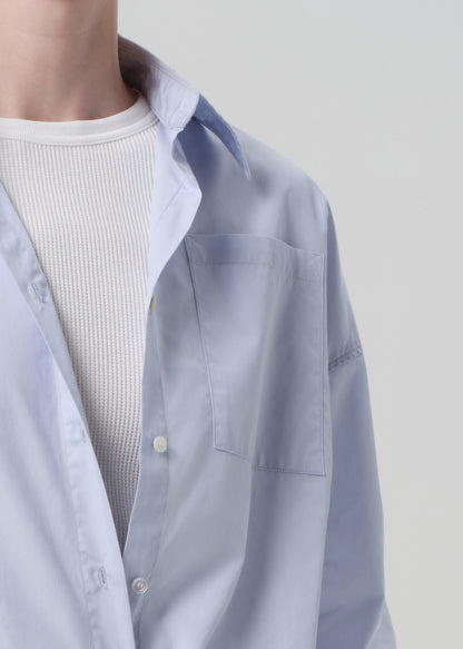 Light blue shirt over a white ribbed sweater on a plain background