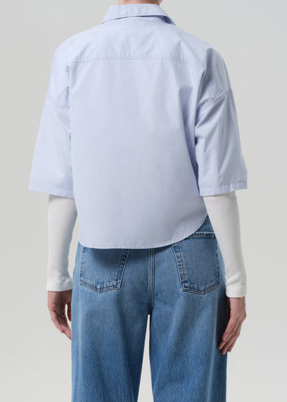 Person wearing a light blue shirt and jeans on a plain background