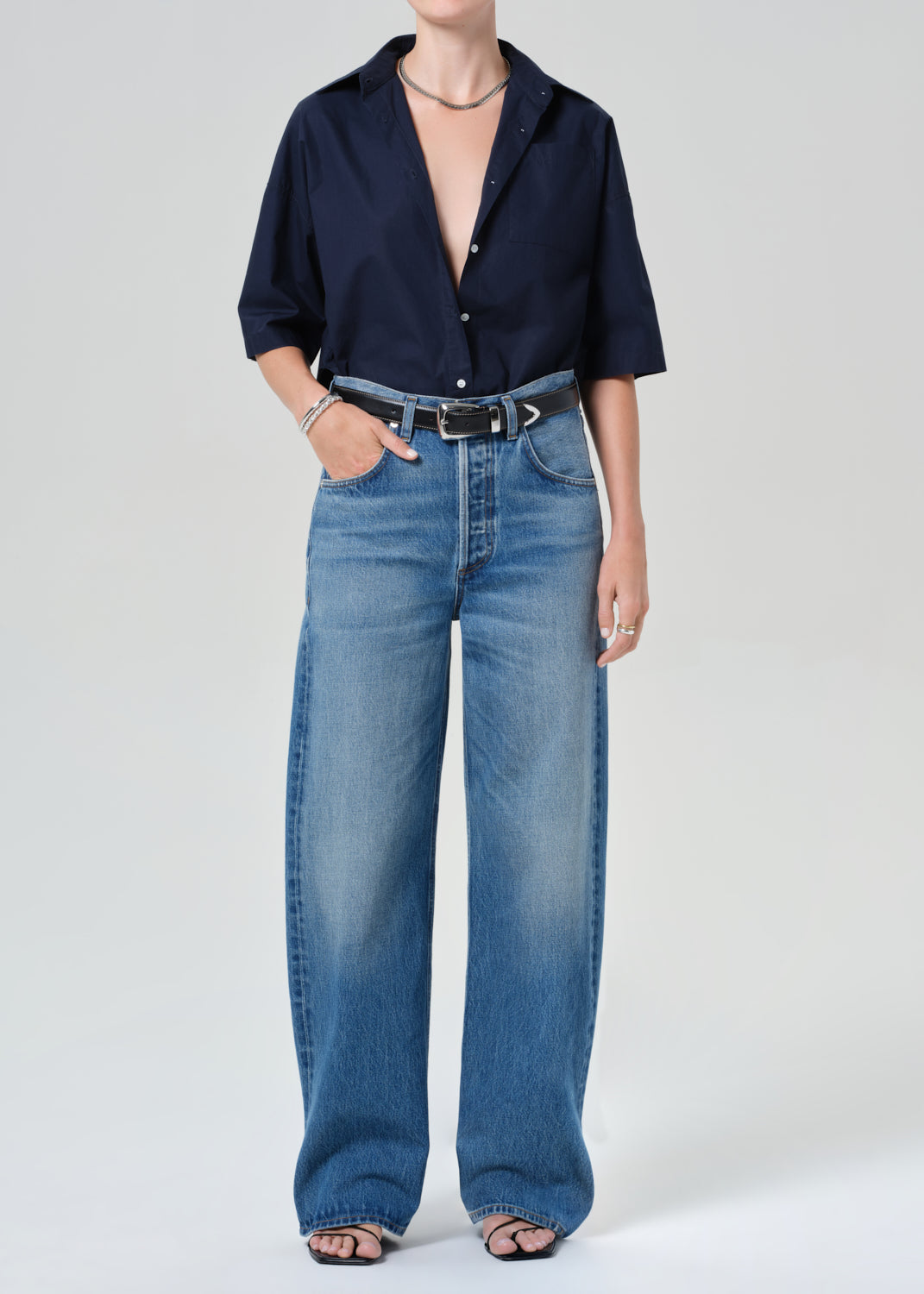 Person wearing a navy shirt and blue jeans on a grey background