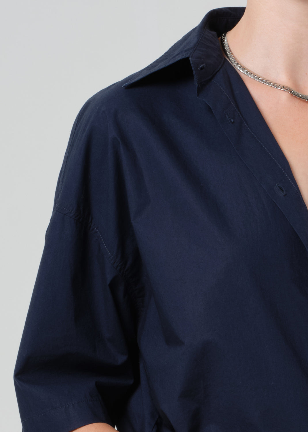 Navy blue shirt worn by a person on a light gray background