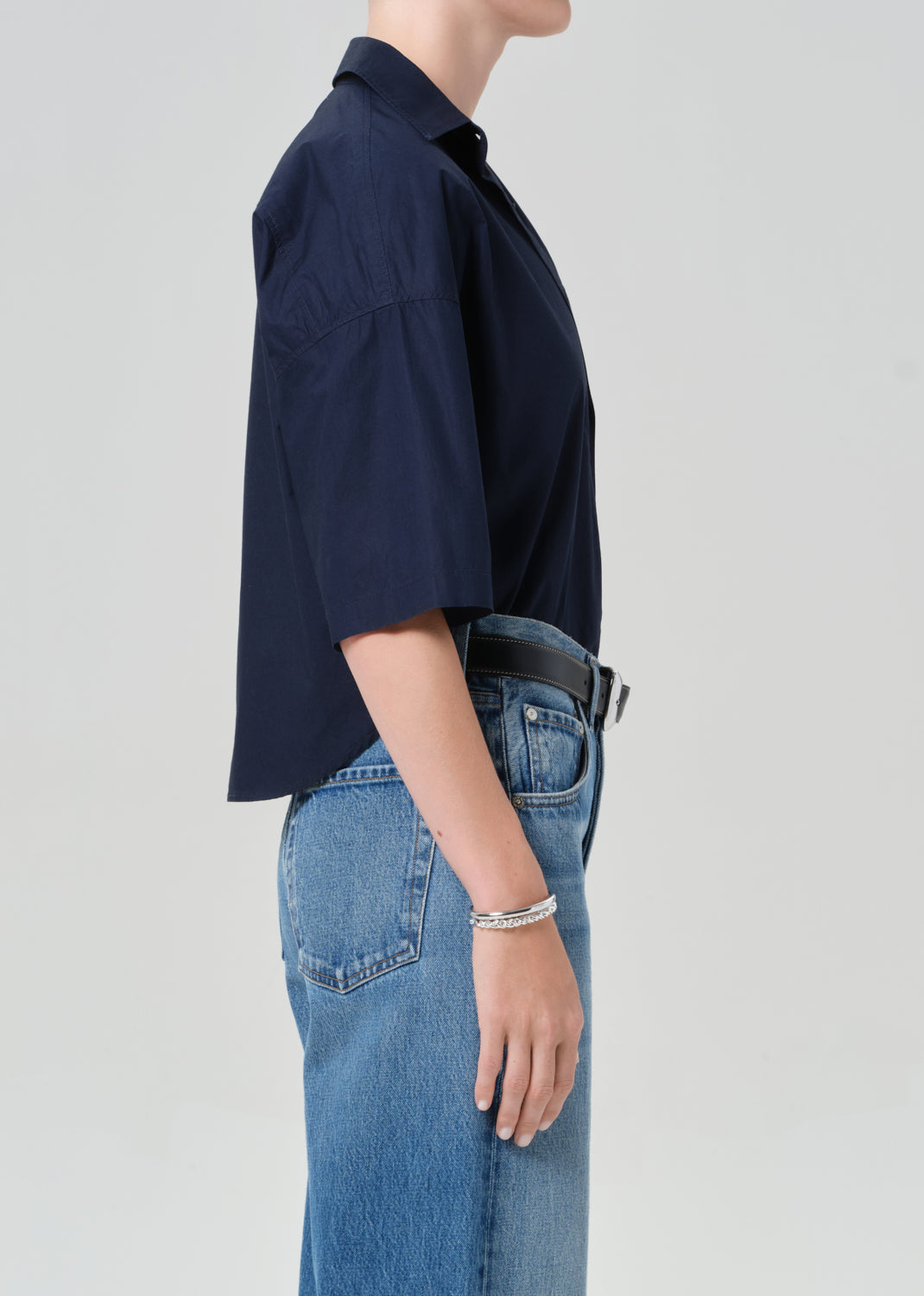 Person wearing a navy shirt and blue jeans on a light gray background