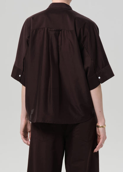 Person wearing a dark brown shirt and pants on a light gray background
