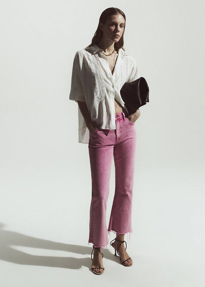 Woman wearing a white shirt and pink pants against a white background