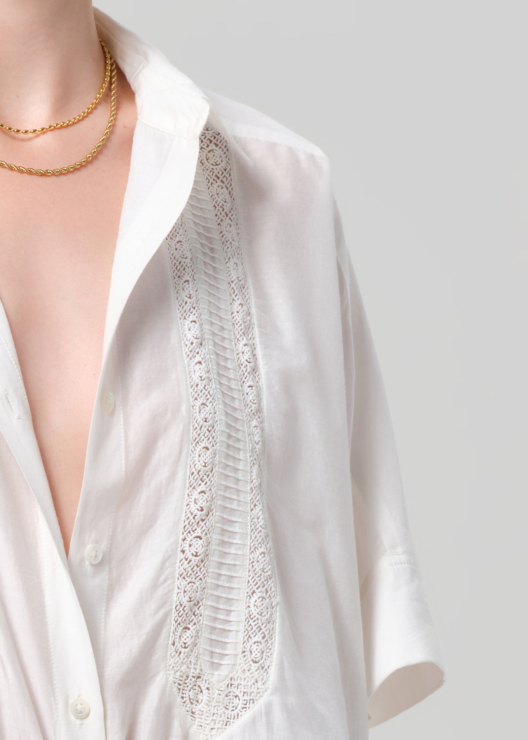 White blouse with lace detailing on a plain background