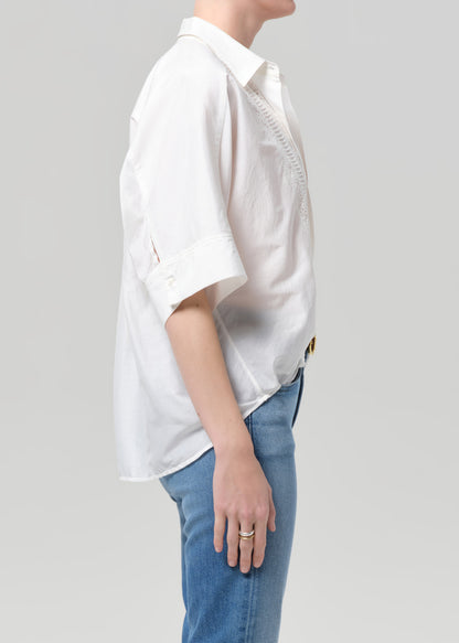 Person wearing a white shirt and blue jeans on a plain background