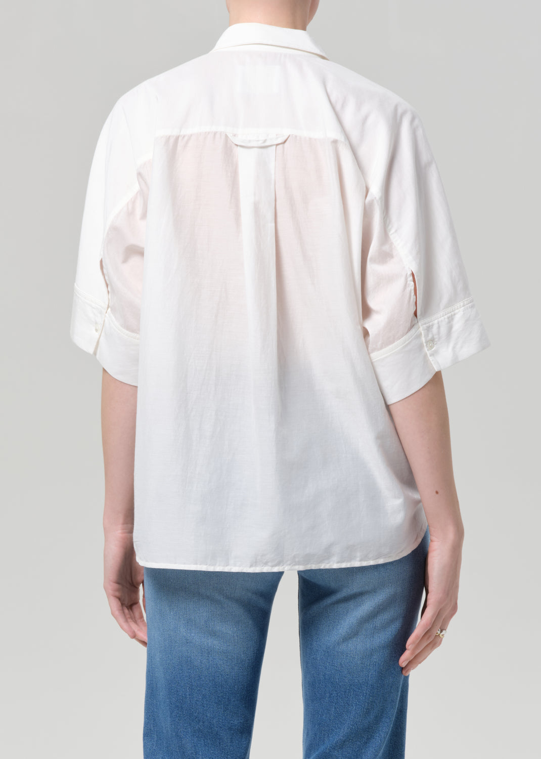 Person wearing a white shirt and blue jeans on a plain background
