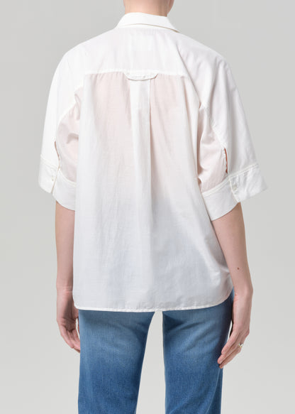 Person wearing a white shirt and blue jeans on a plain background