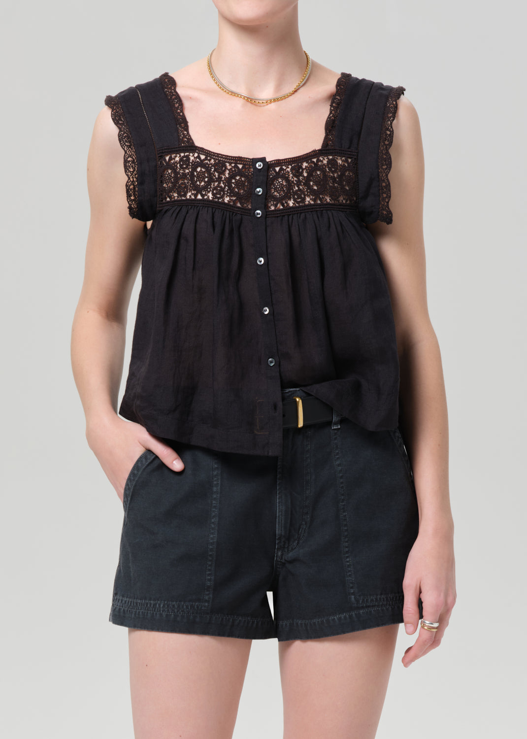 Black sleeveless top with lace details and black shorts on a grey background