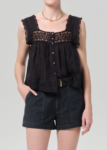 Black sleeveless top with lace details and black shorts on a grey background