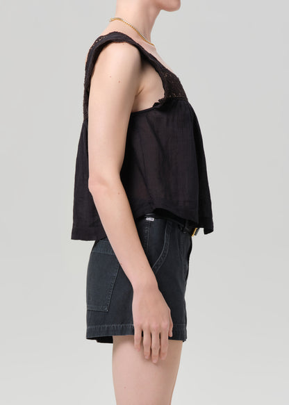 Person wearing a black sleeveless top and black shorts on a grey background