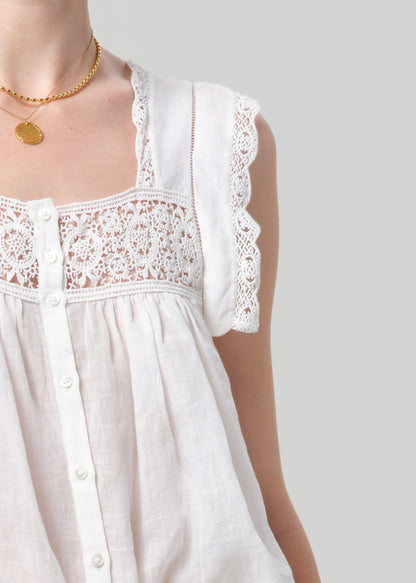 Person wearing a white lace top and olive pants on a gray background