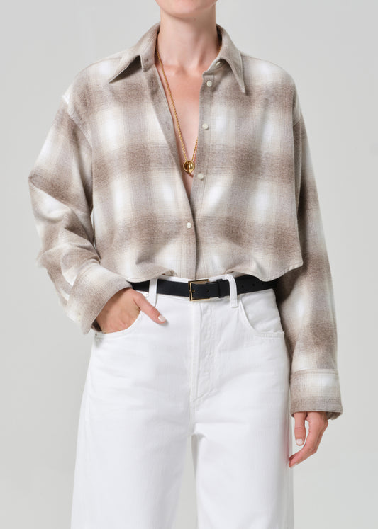 Person wearing a plaid shirt and white jeans on a plain background