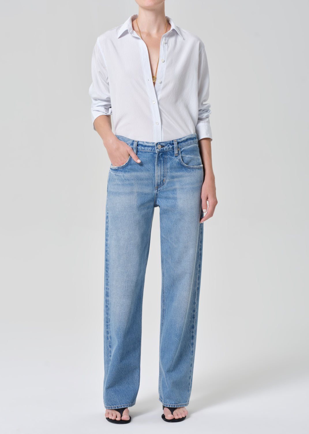 Person wearing a light blue shirt and jeans on a white background