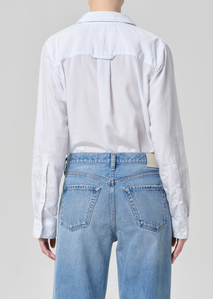 Person wearing a light blue shirt and jeans on a plain background