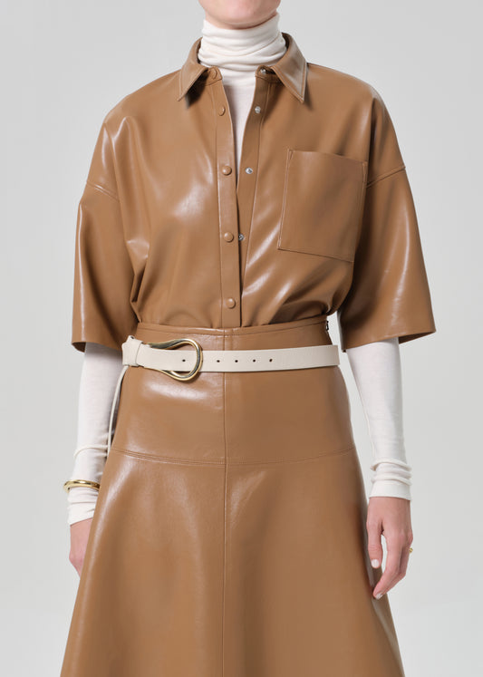 Person wearing a brown leather outfit with a white belt on a gray background