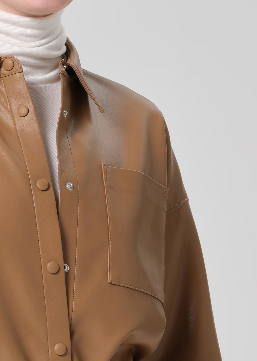 Brown leather jacket with a white turtleneck on a light gray background