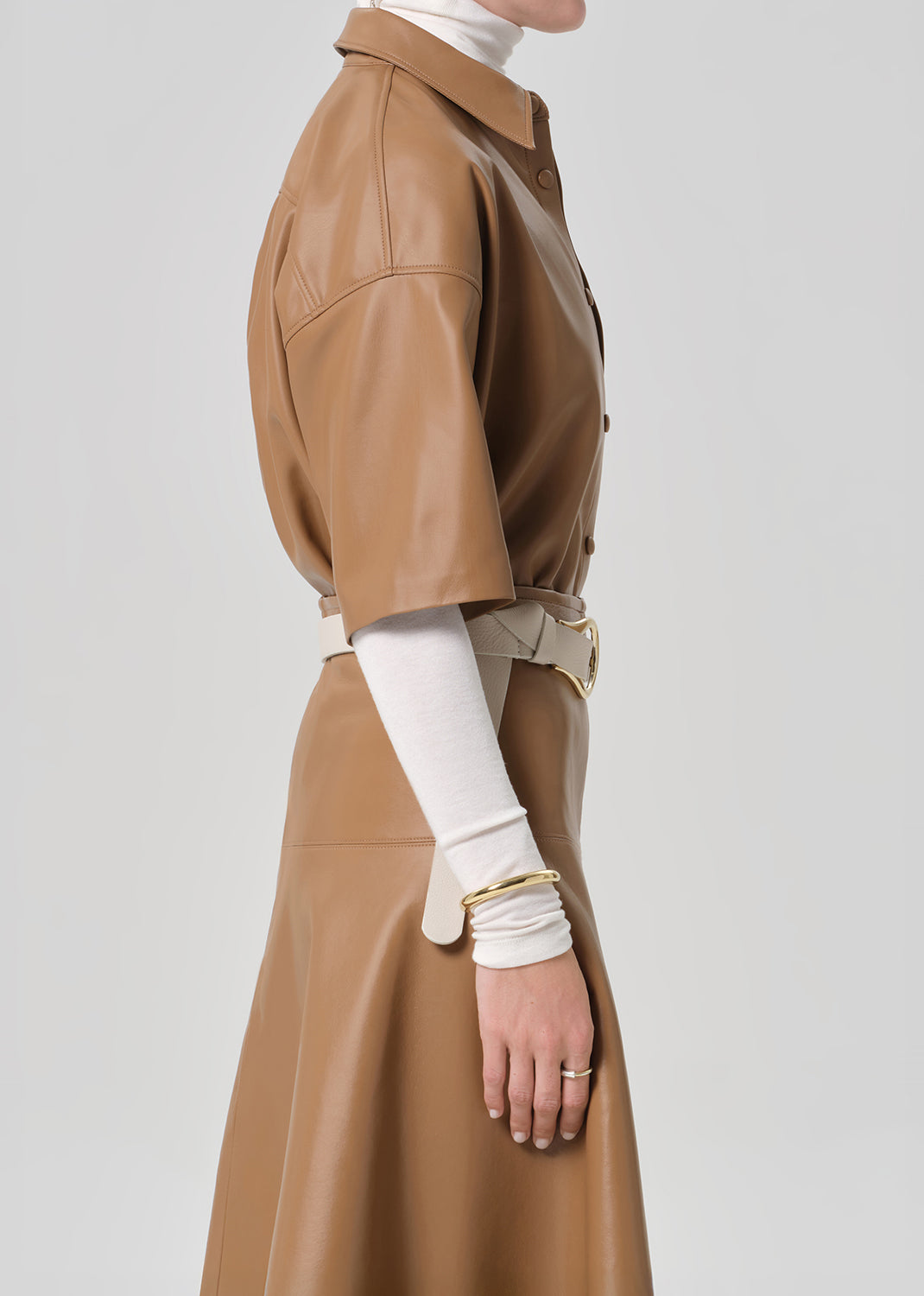 Brown leather coat worn by a person on a light gray background