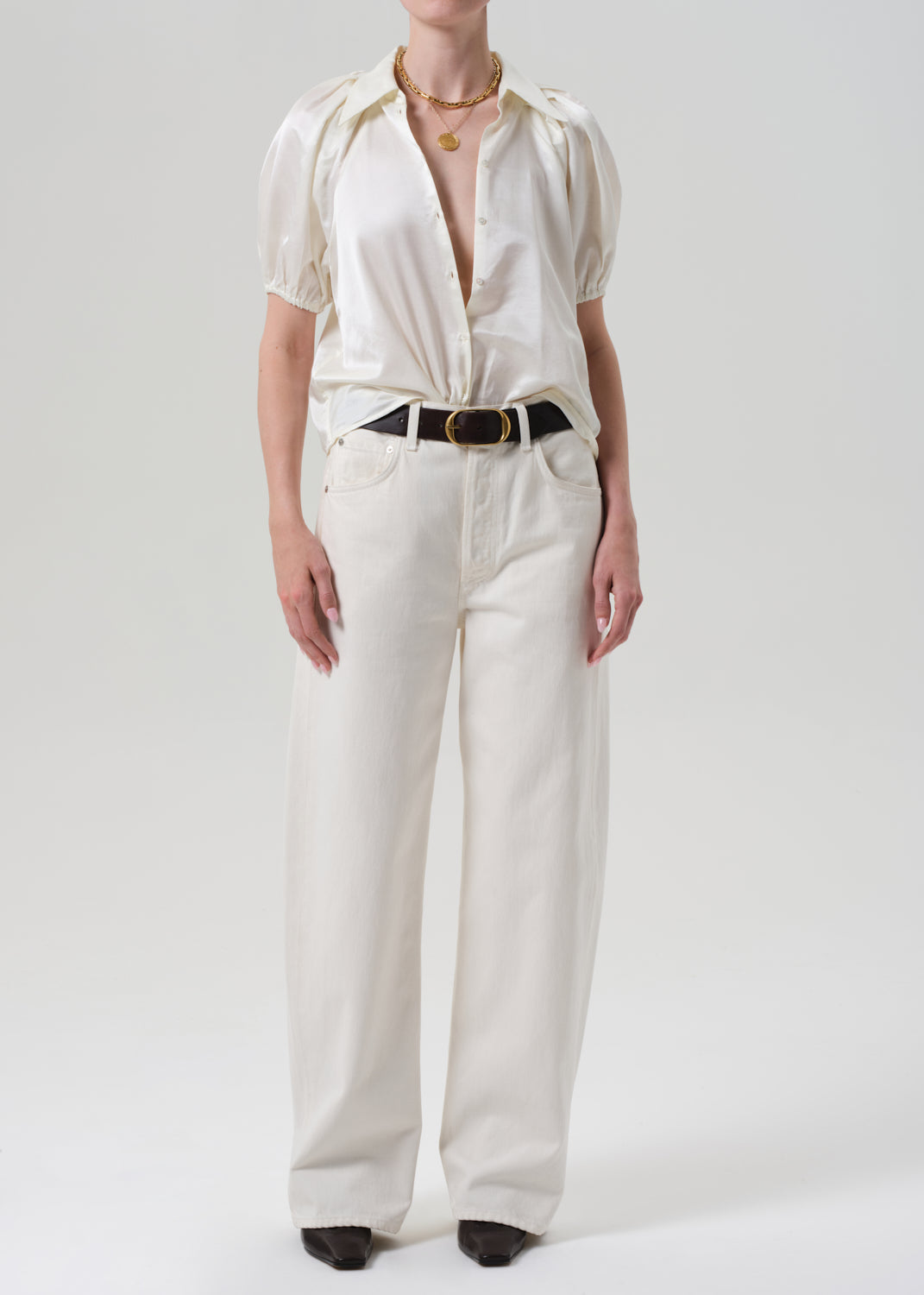 Person wearing a white outfit with a belt on a plain background