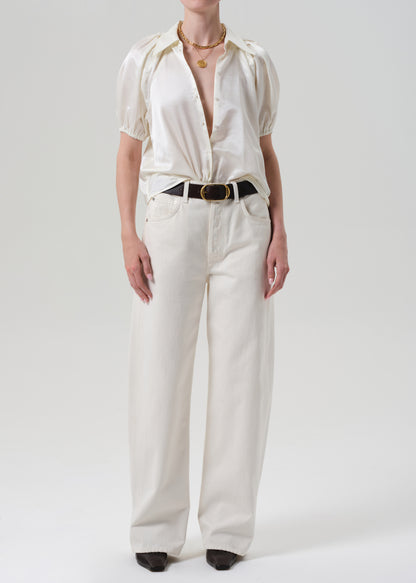 Person wearing a white outfit with a belt on a plain background
