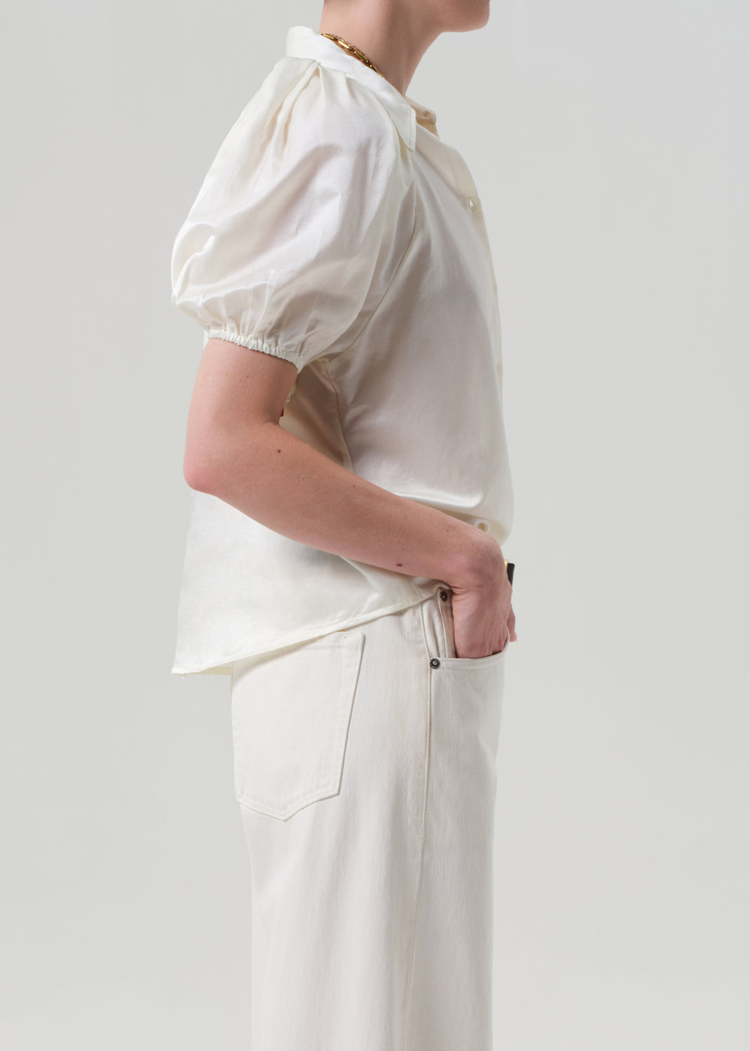 Person wearing a white blouse with puffed sleeves on a plain background