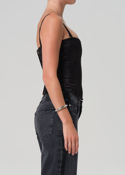 Person wearing a black corset and dark jeans on a plain background