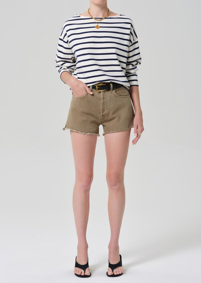 Person wearing a striped shirt and beige shorts on a plain background