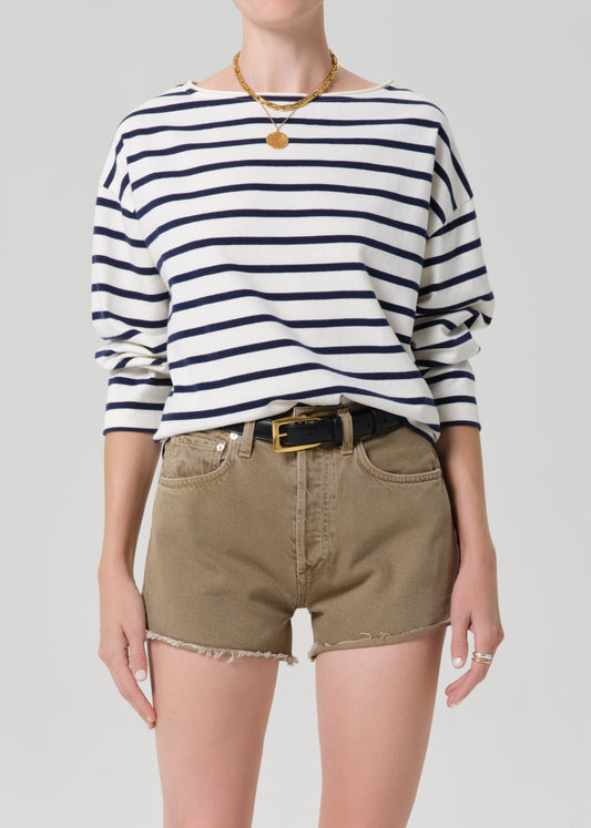 Person wearing a striped shirt and beige shorts on a plain background