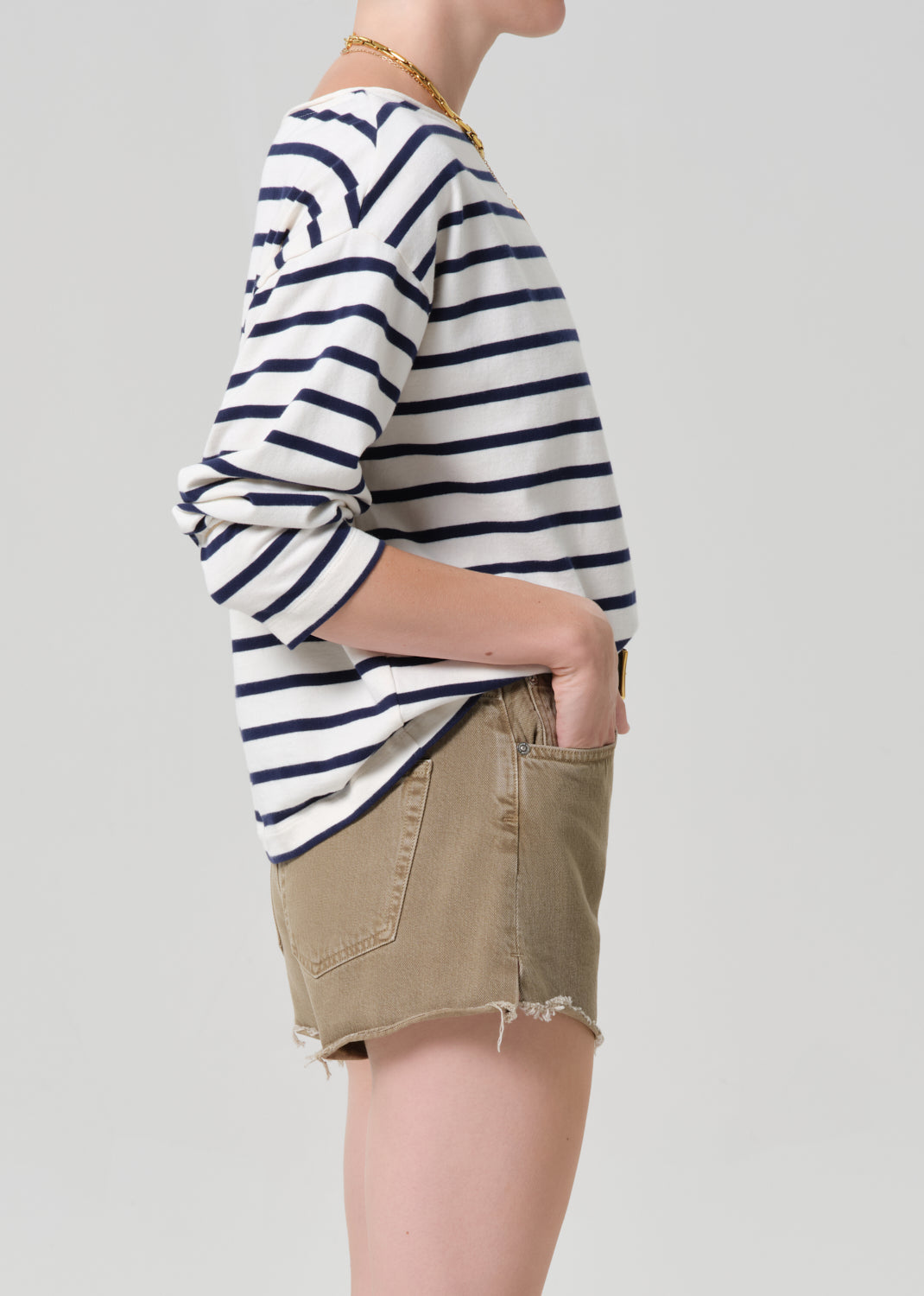 Person wearing a striped shirt and beige shorts on a plain background