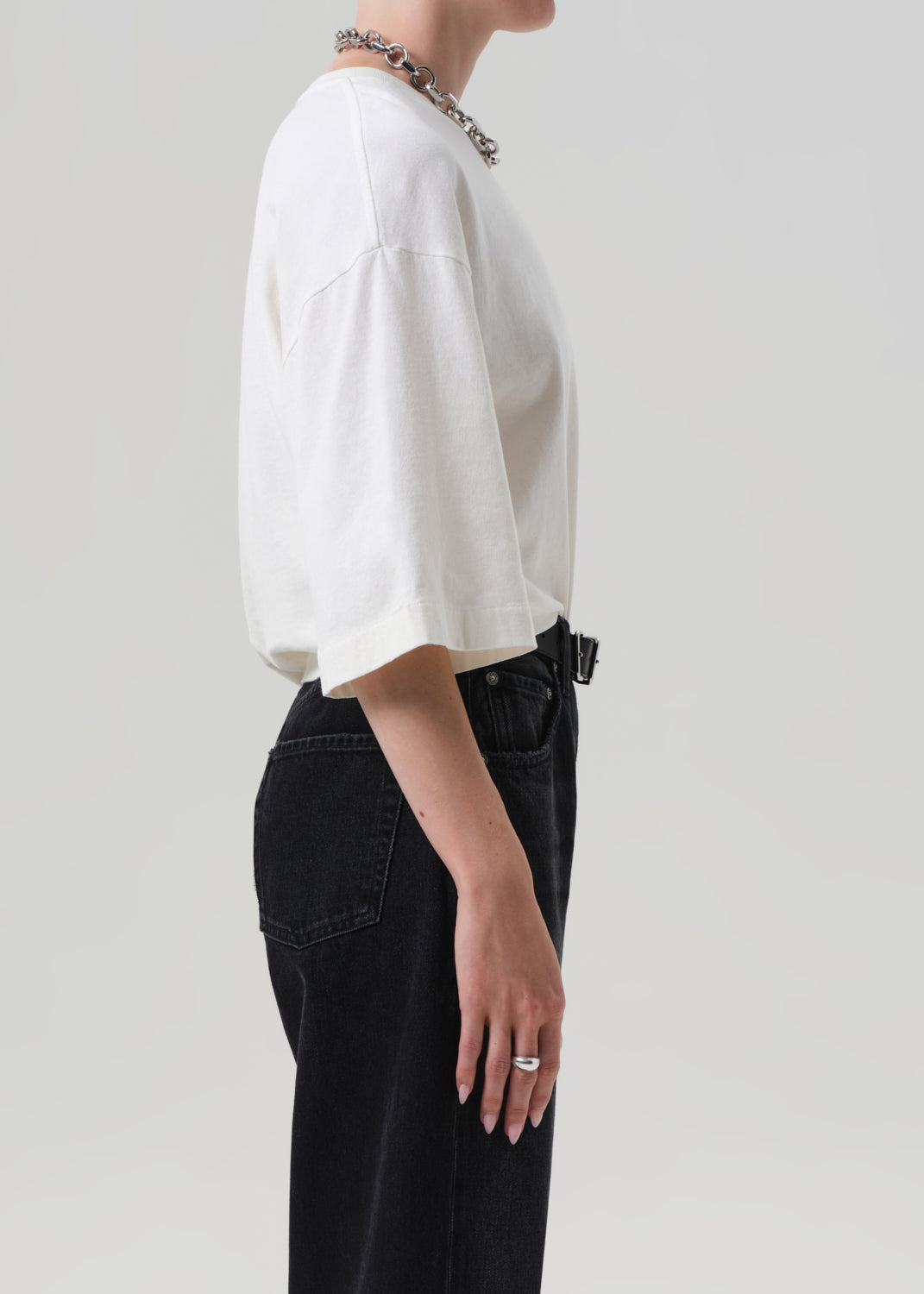 Person wearing a white shirt and black pants on a plain background