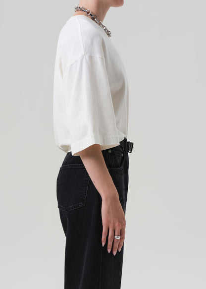 Person wearing a white shirt and black pants on a plain background
