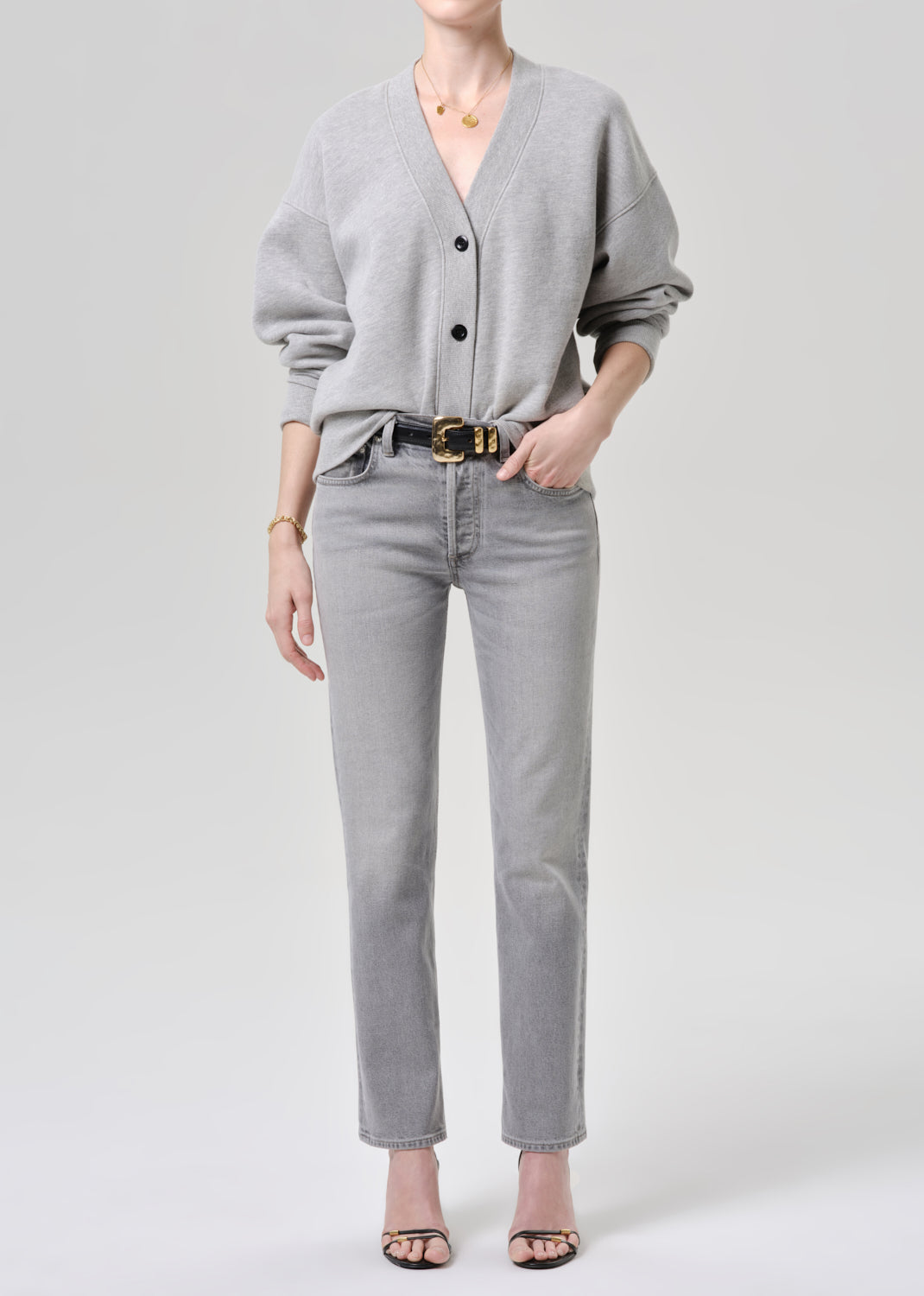 Person wearing a grey cardigan and jeans on a grey background