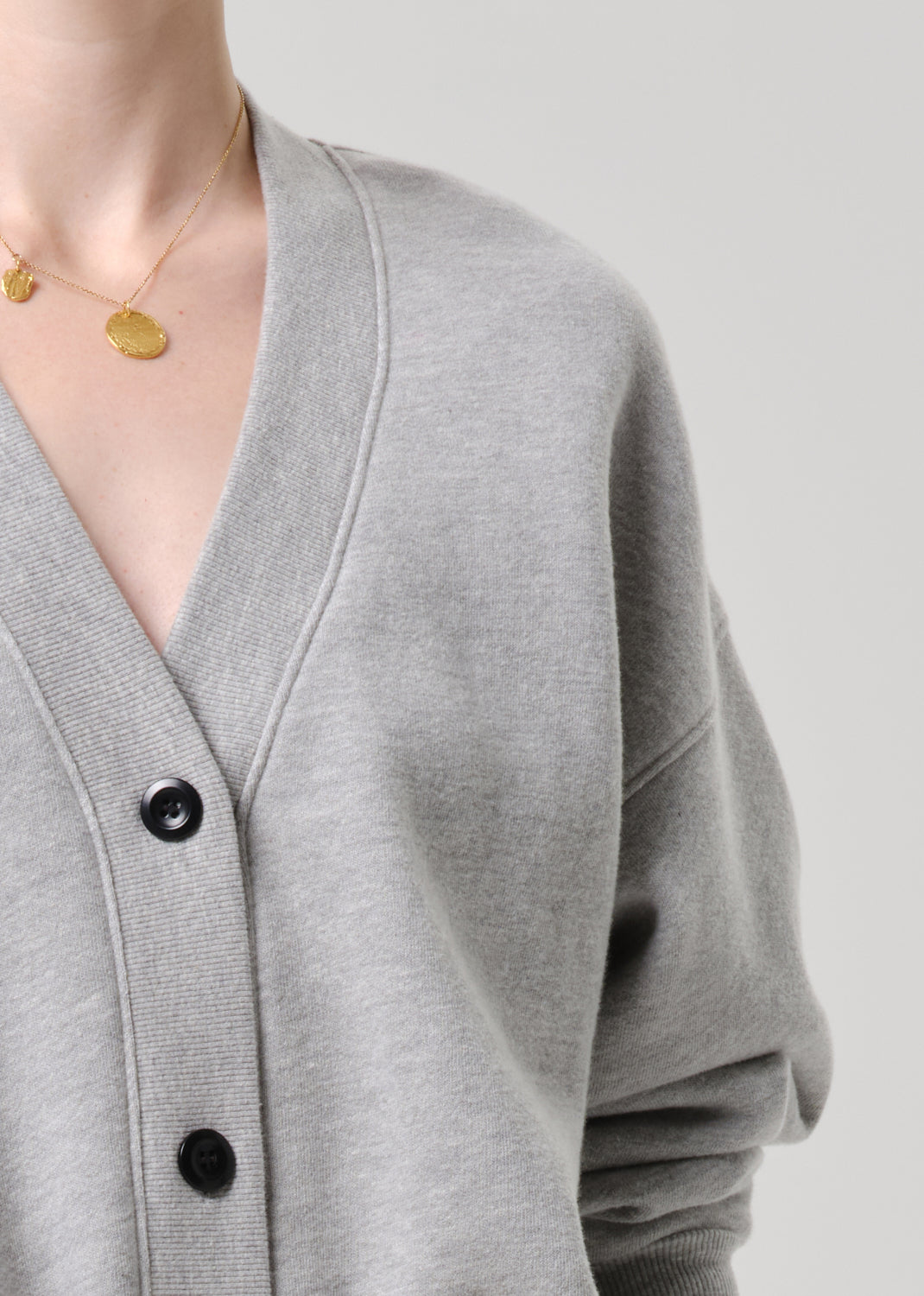 Grey cardigan with black buttons on a grey background