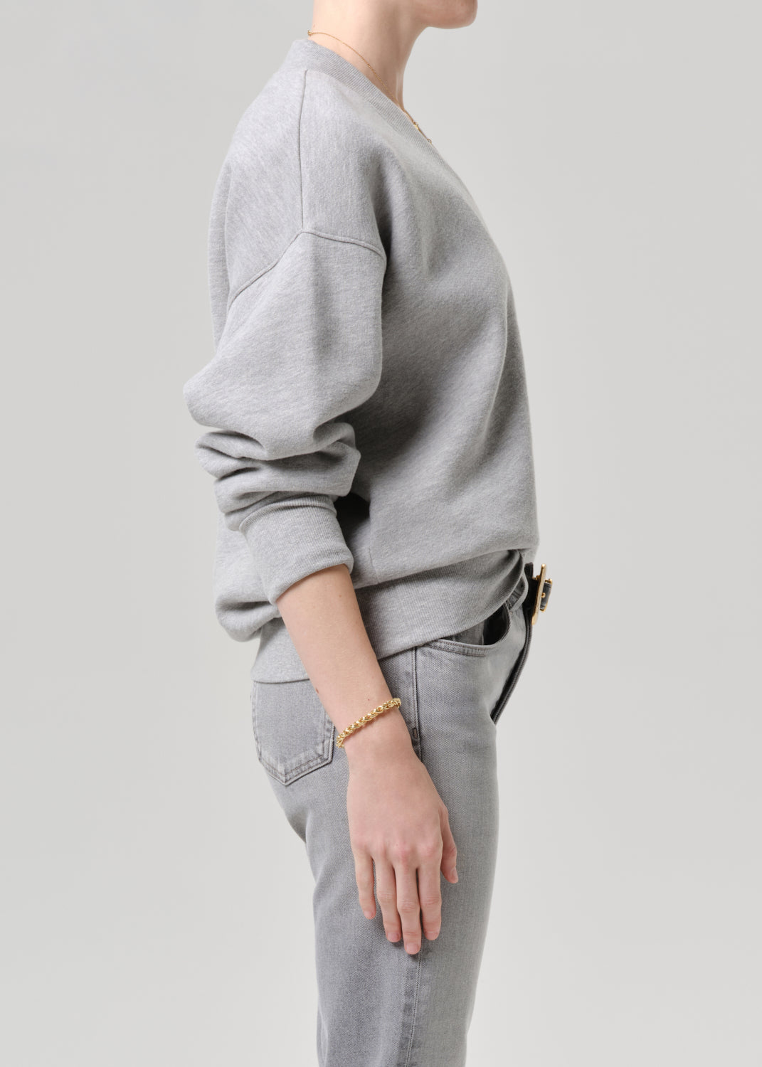 Person wearing a grey sweatshirt and jeans on a grey background