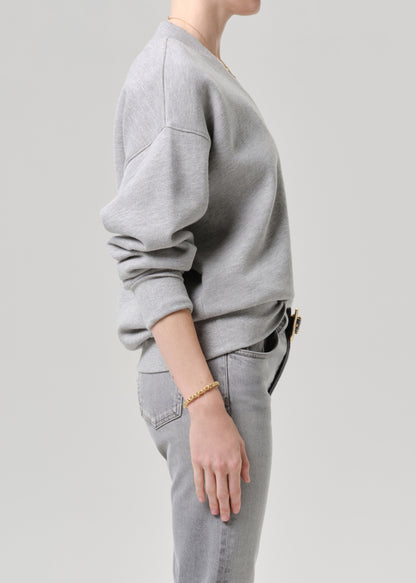 Person wearing a grey sweatshirt and jeans on a grey background