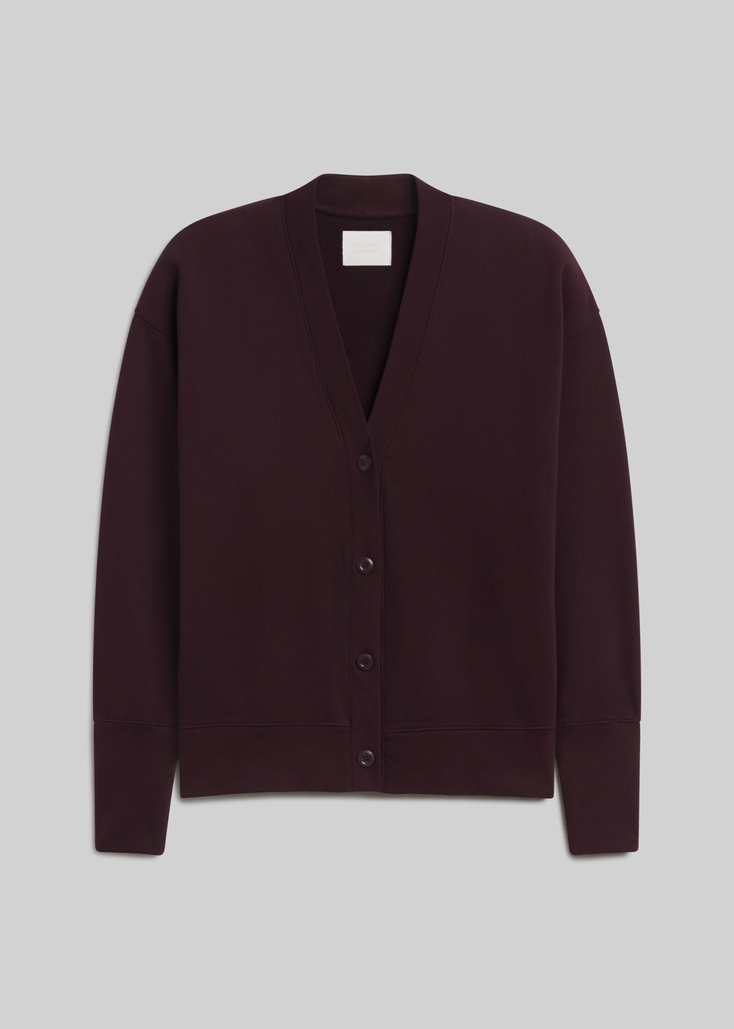 Deep burgundy fleece cardigan featuring a relaxed silhouette, deep V-neckline, four-button front closure, dropped shoulders, long sleeves, and ribbed cuffs and hem, front view on a grey background.