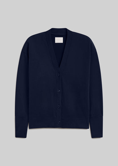 Navy fleece cardigan featuring a relaxed silhouette, deep V-neckline, four-button front closure, dropped shoulders, long sleeves, and ribbed cuffs and hem, front view on a grey background.
