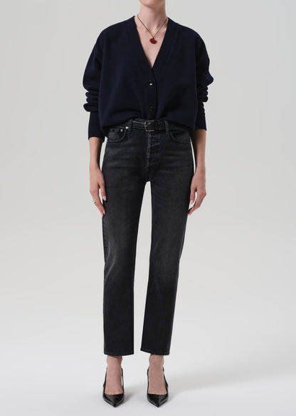 Person wearing a navy cardigan and dark jeans on a plain background