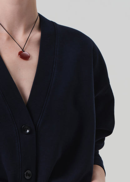 Person wearing a navy cardigan and dark jeans on a plain background