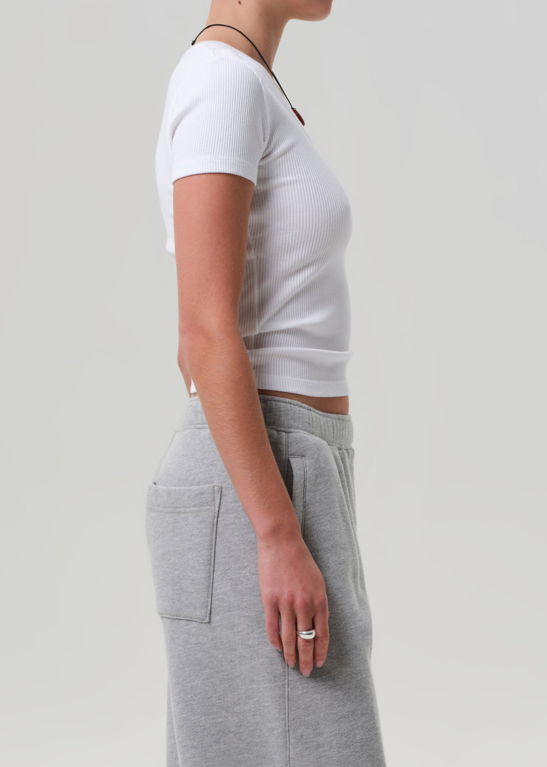 Person wearing a white crop top and gray sweatpants on a plain background