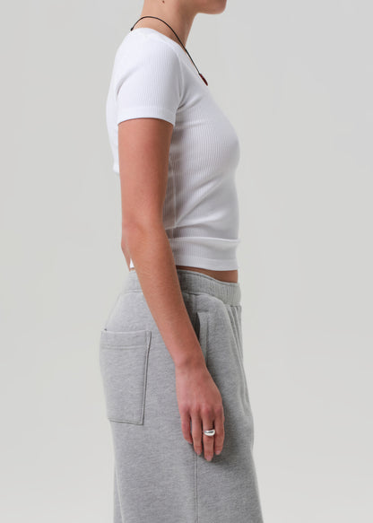 Person wearing a white crop top and gray sweatpants on a plain background