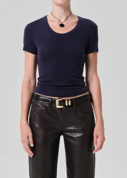 Person wearing a dark blue top and brown leather pants on a gray background