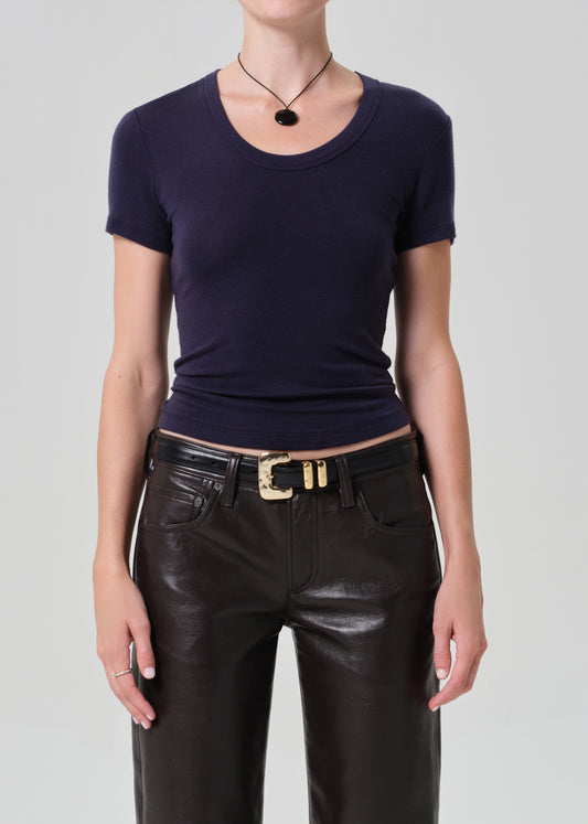 Person wearing a dark blue top and brown leather pants on a gray background