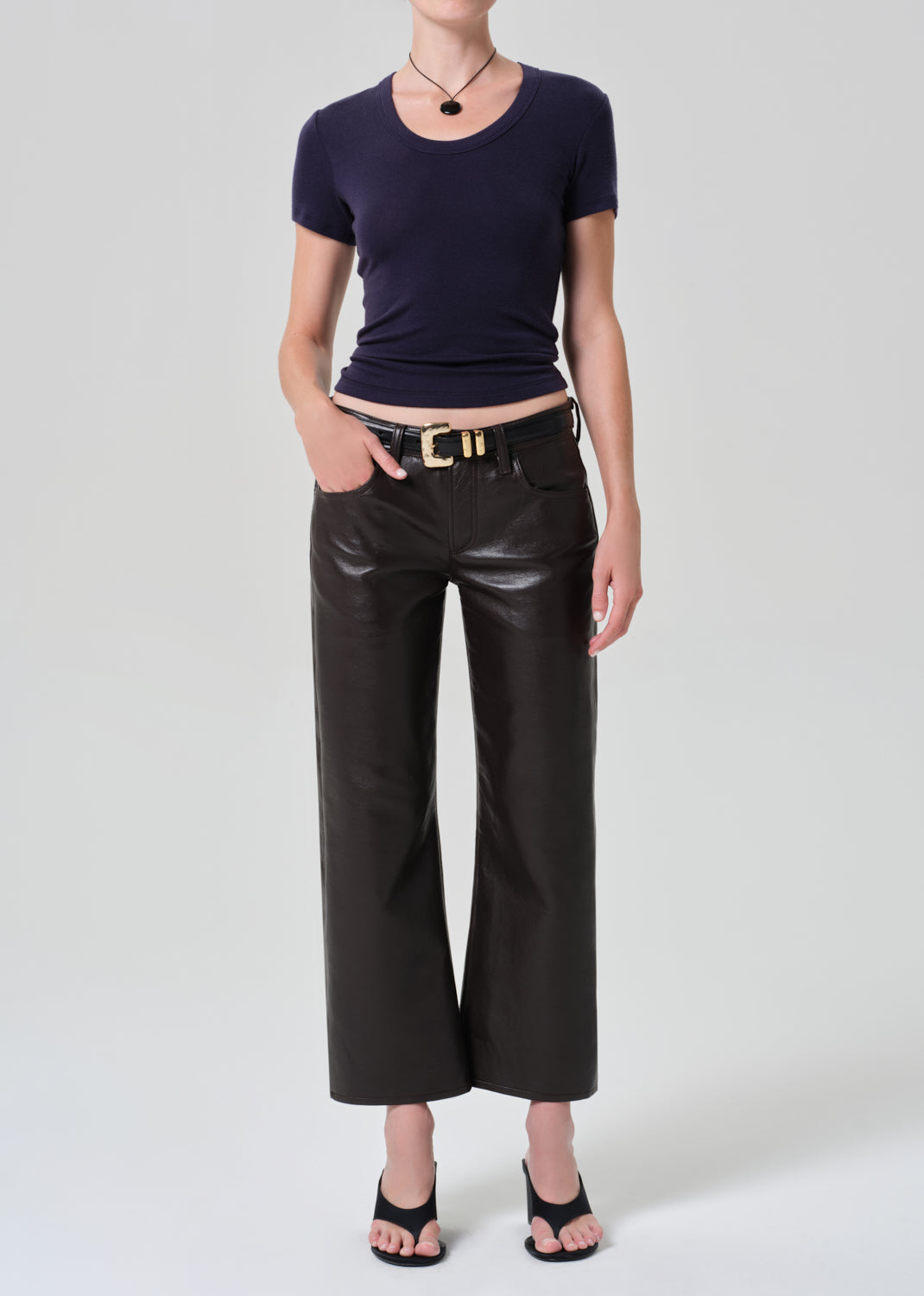 Person wearing a dark blue top and brown leather pants on a gray background