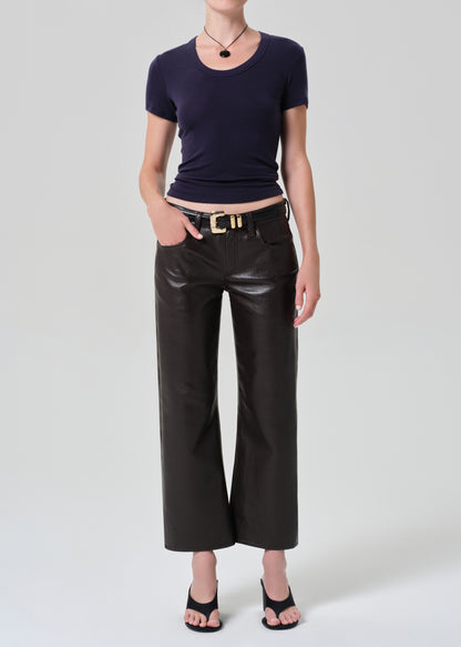 Person wearing a dark blue top and brown leather pants on a gray background