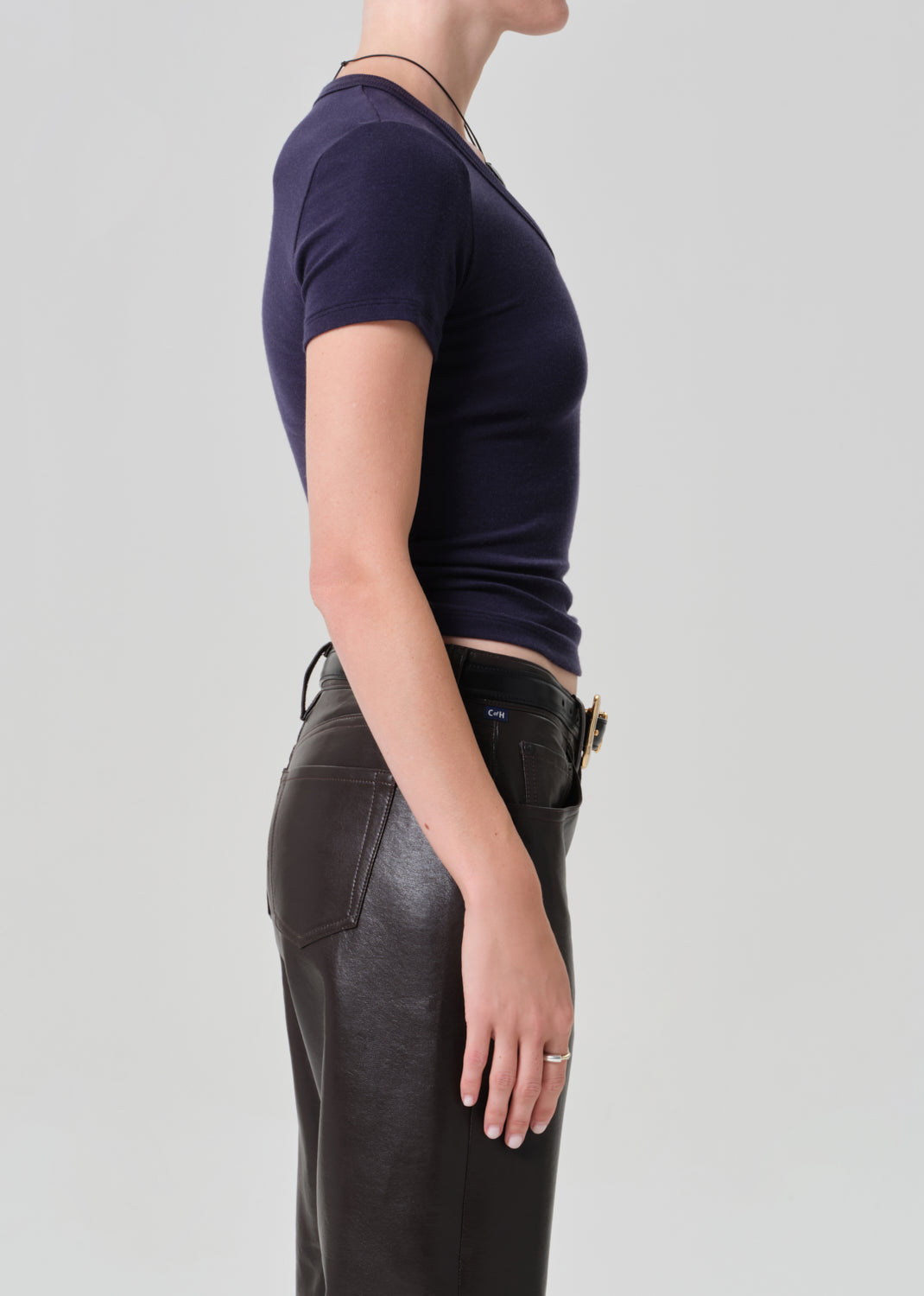 Person wearing a dark blue top and brown leather pants on a gray background