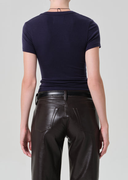 Person wearing a dark blue top and brown leather pants on a gray background