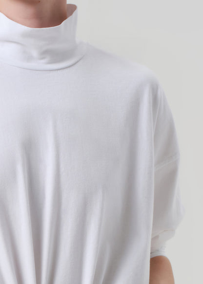 White turtleneck sweater worn by a person on a plain background