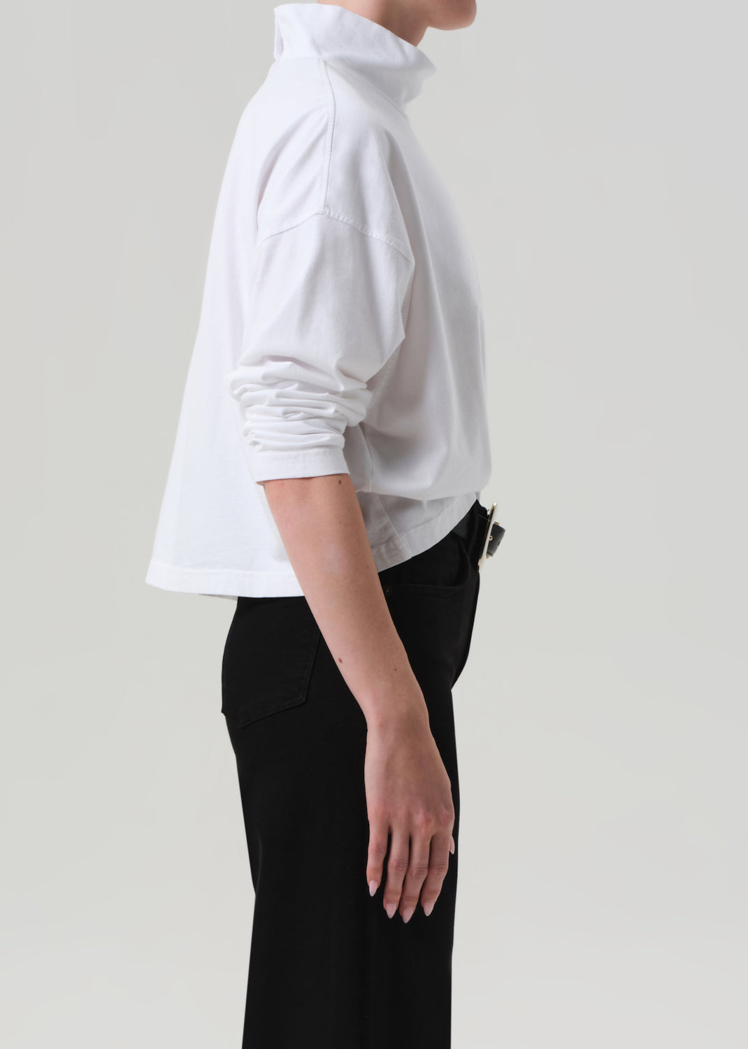 Person wearing a white blouse and black pants on a plain background